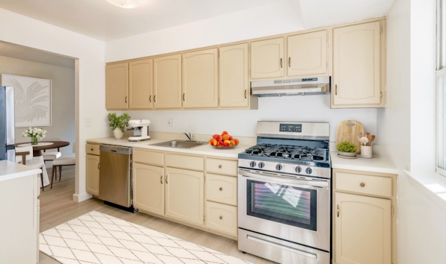 Spacious and well lit kitchen with wood floors and stainless steel appliances with access to the living room 