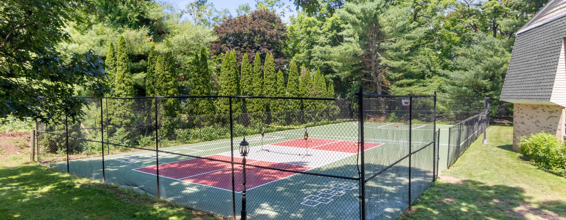 View of fenced sport court with lush landscaping surrounding 